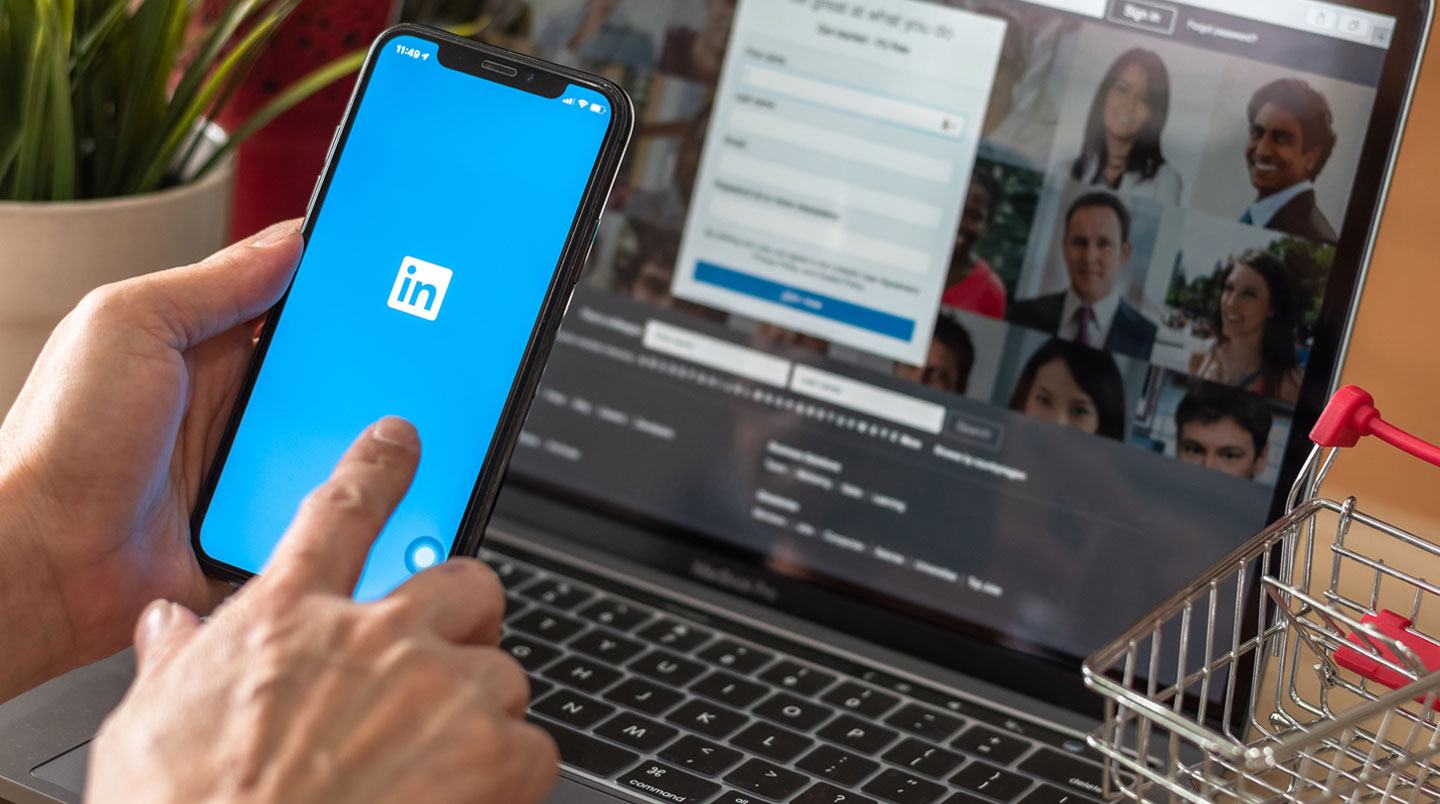 Professionnel travaillant sur ordinateur portable affichant une interface LinkedIn en français avec liste de prospects, dans un bureau moderne éclairé naturellement